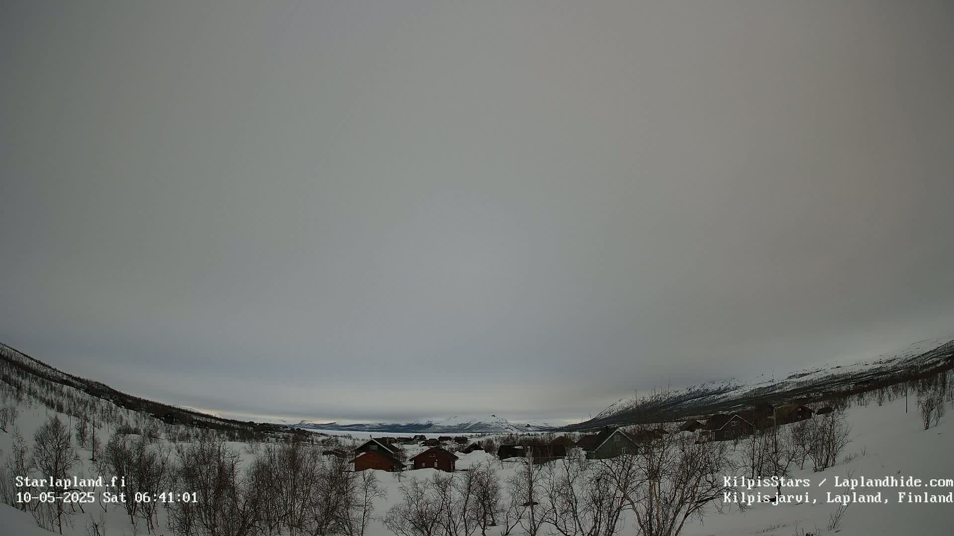 A snow-covered landscape with a small cluster of houses is visible under an overcast sky.
