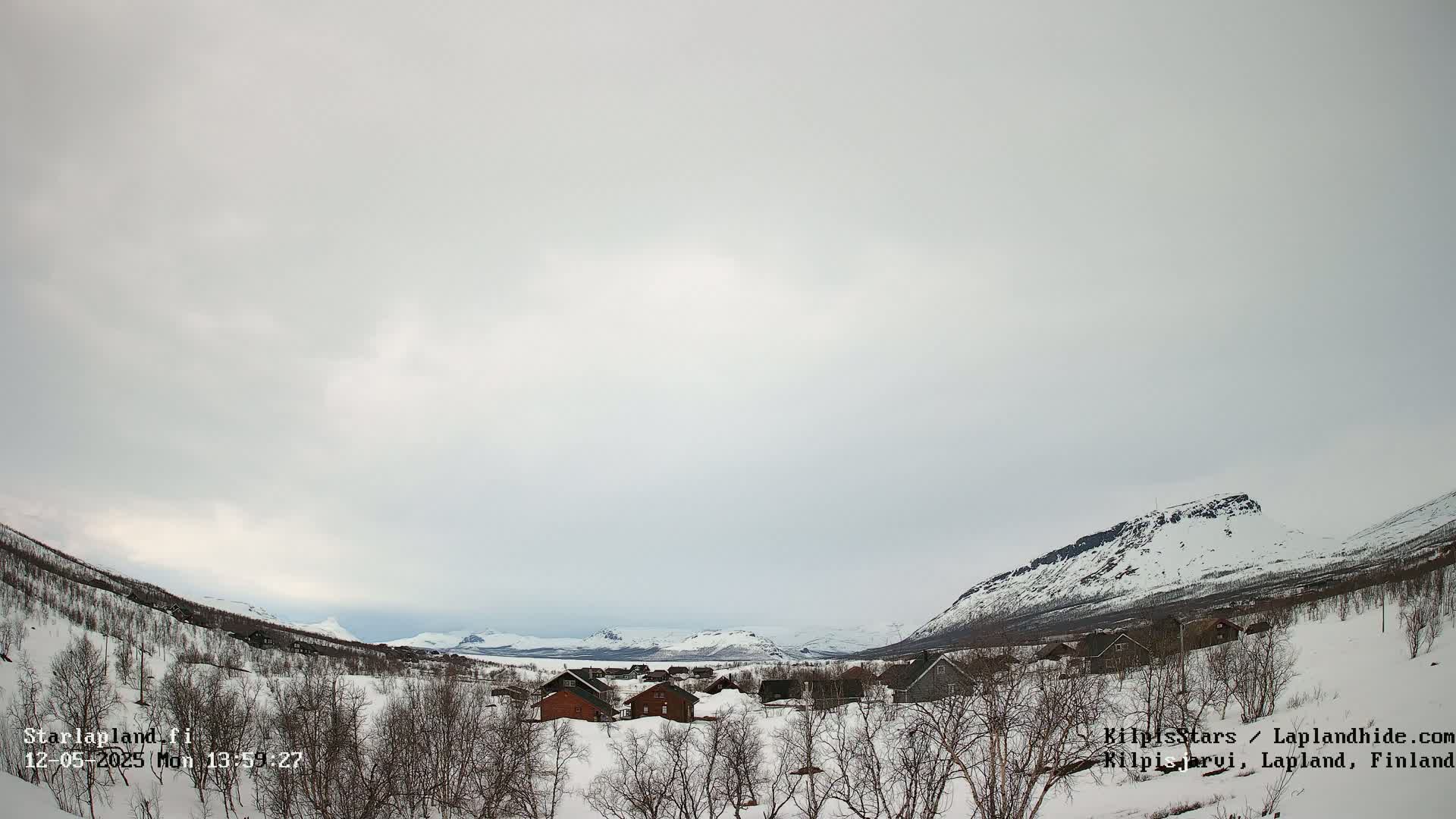 A snow-covered village nestled between mountains under an overcast sky.