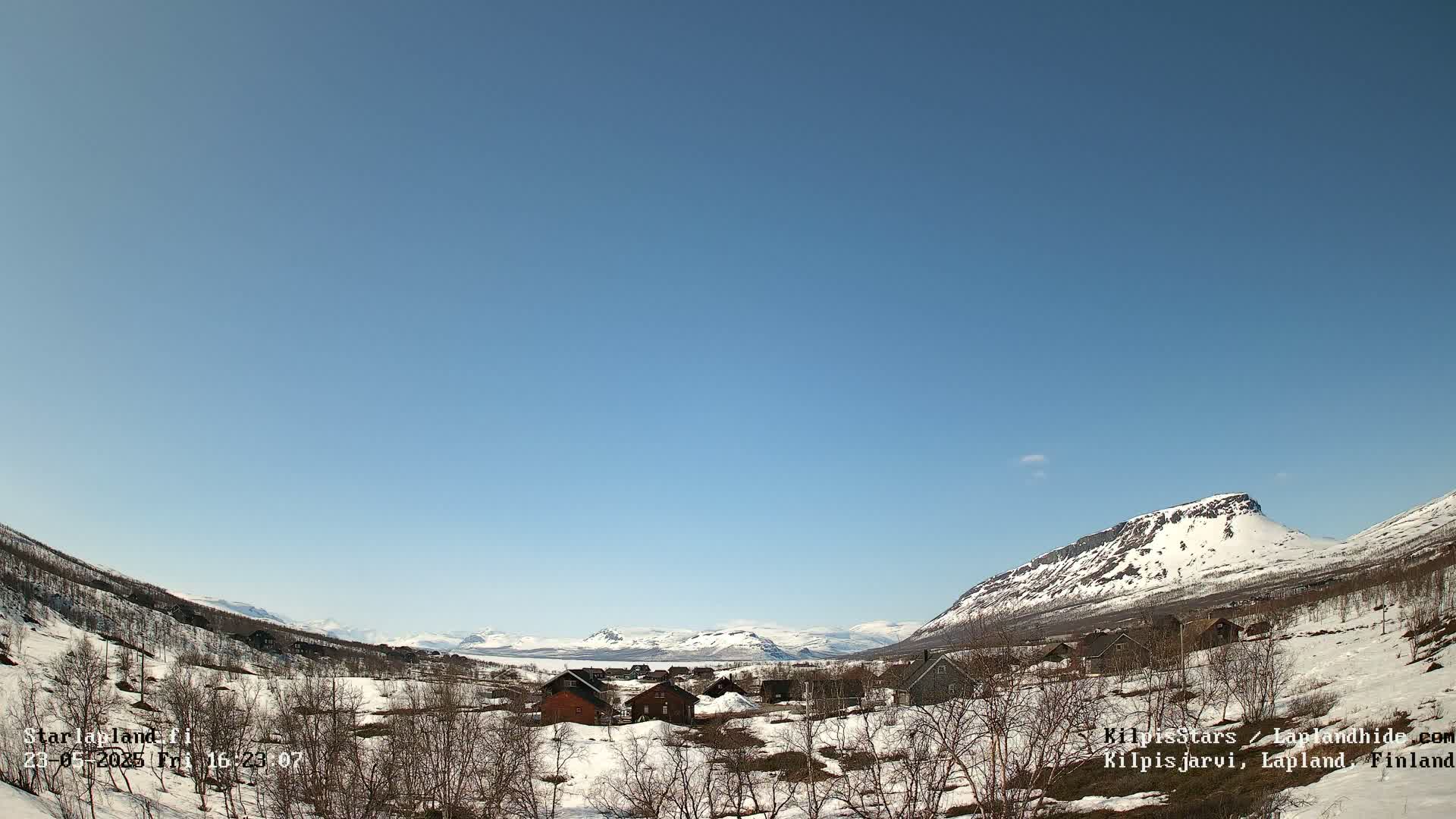 A small village nestled in a snow-dusted valley between mountains under a clear blue sky.