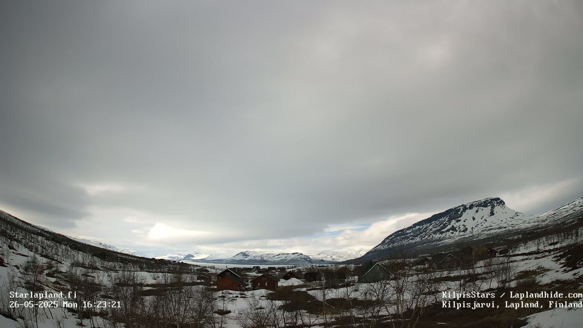 A small village nestled in a snow-dusted valley between mountains under an overcast sky.