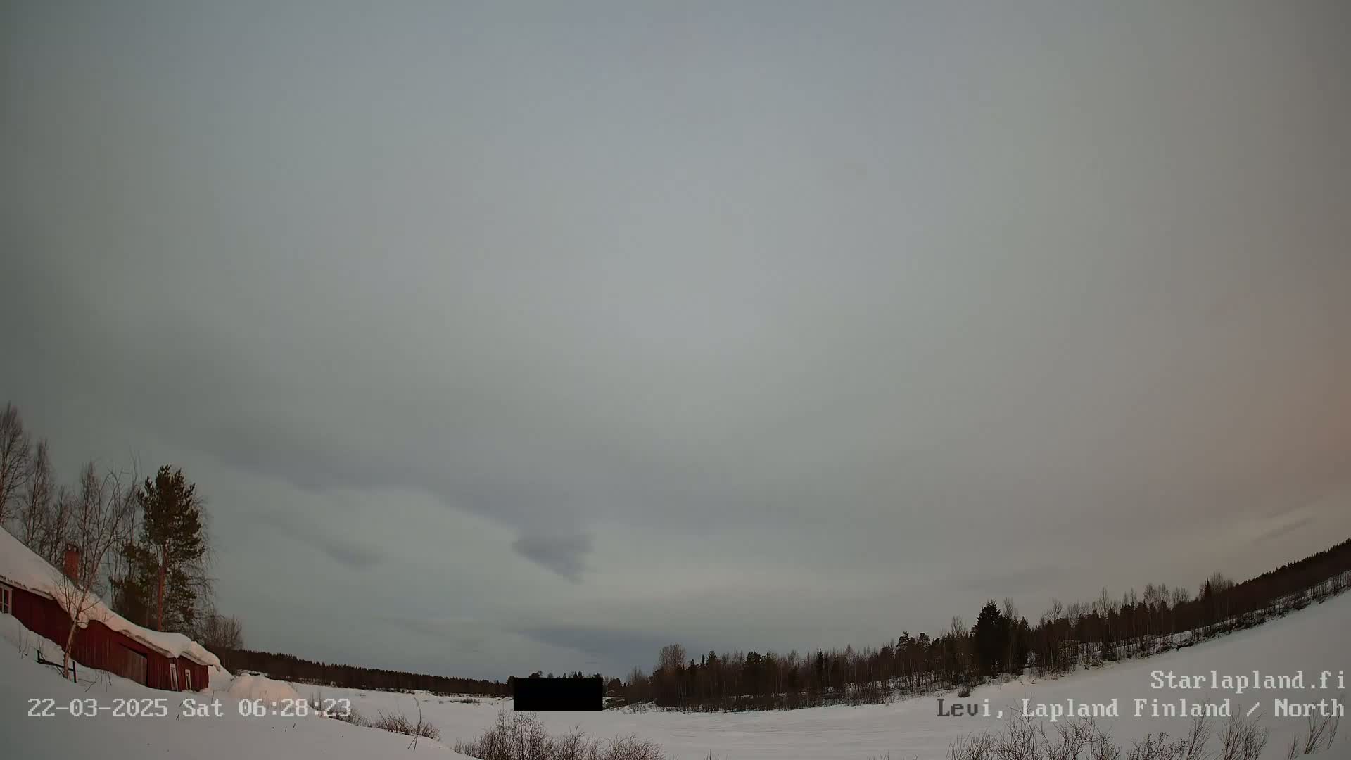 A snowy landscape with a red building and trees under an overcast sky.