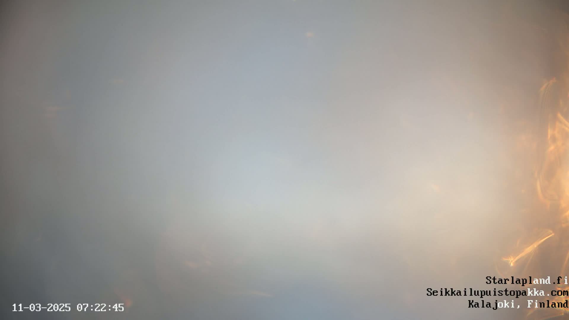 A hazy, light-grey sky shows a faint orange glow near the bottom right corner.
