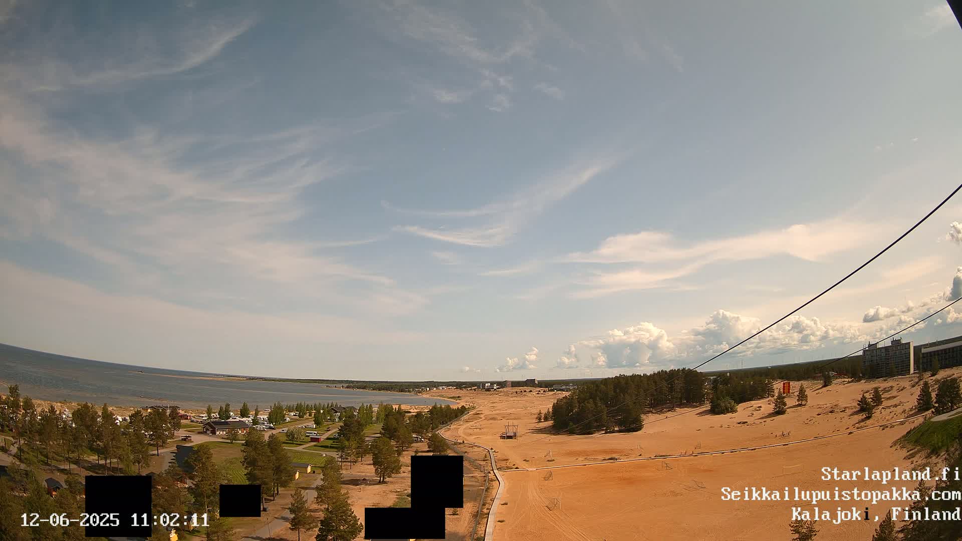 A high-angle view of a sandy landscape near a body of water under a partly cloudy sky.