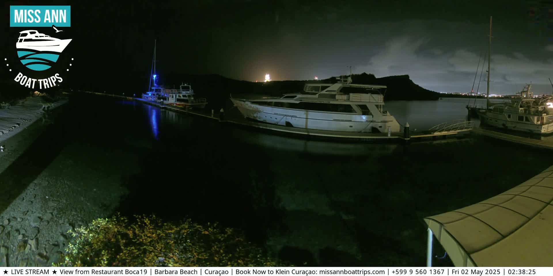 Several boats are docked at a marina at night under a partly cloudy sky.