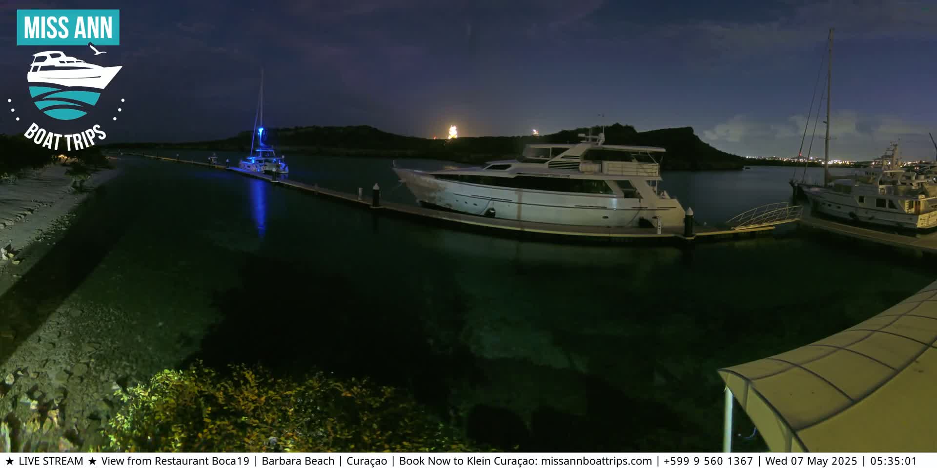 Several yachts are moored at a marina at night, under a dark sky.