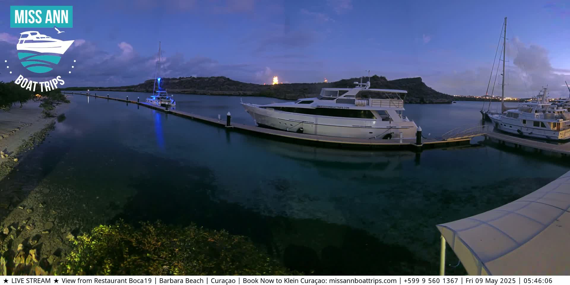 Several yachts are docked at a marina at twilight, under a mostly clear sky.
