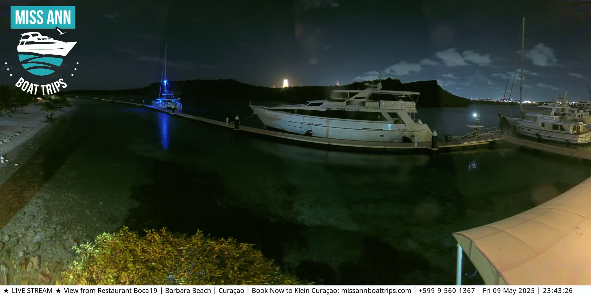 Several boats are docked at a marina at night under a partly cloudy sky.
