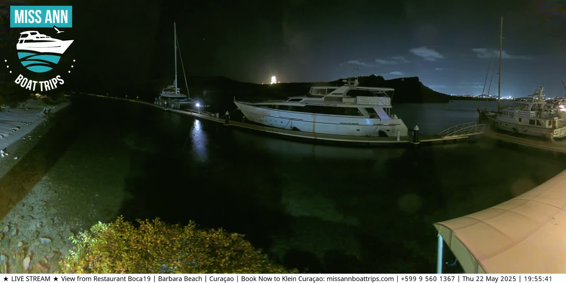 Several boats are docked at a marina at night under a partly cloudy sky.