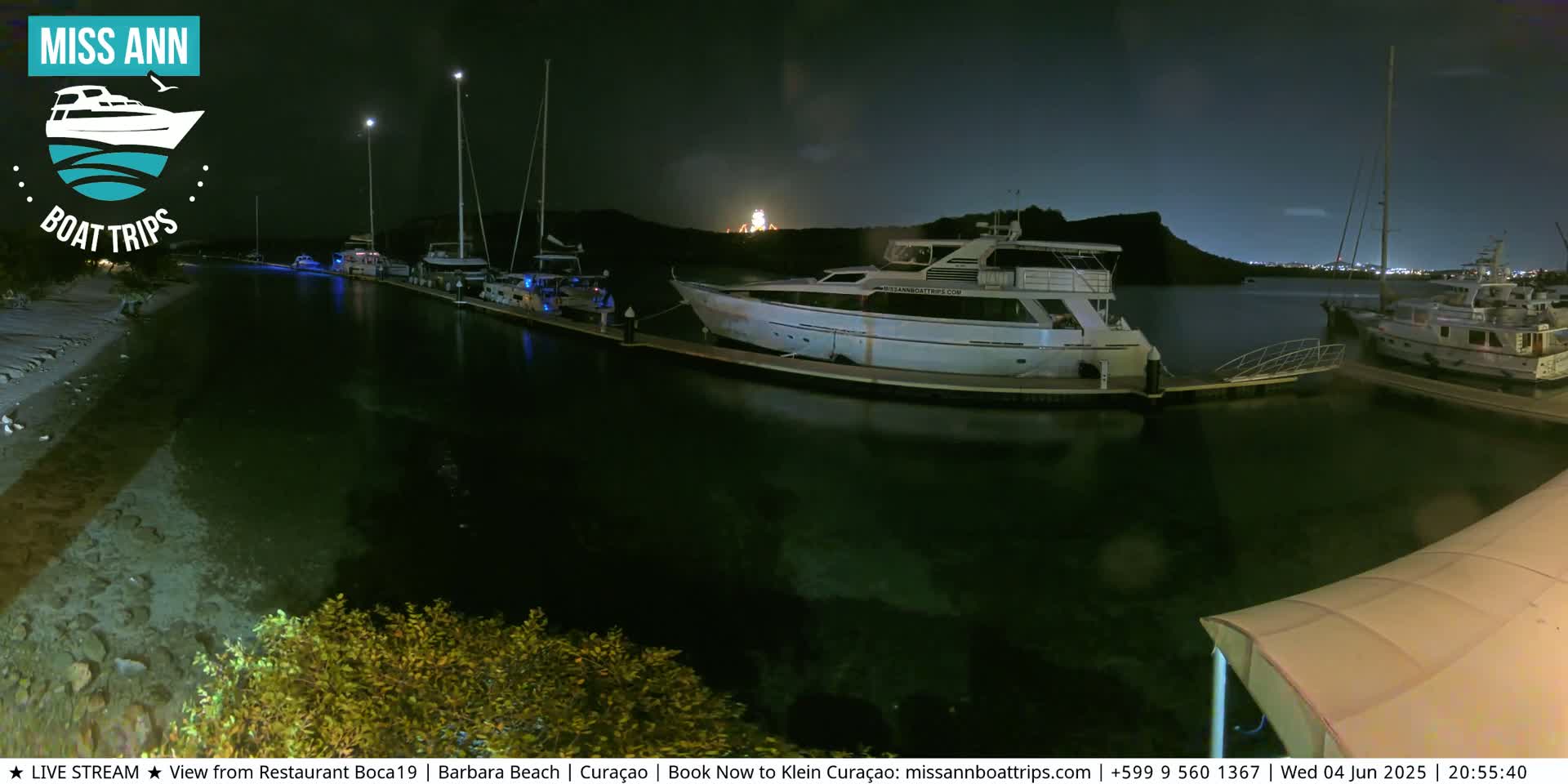Several yachts and sailboats are docked at a marina at night under a dark sky.
