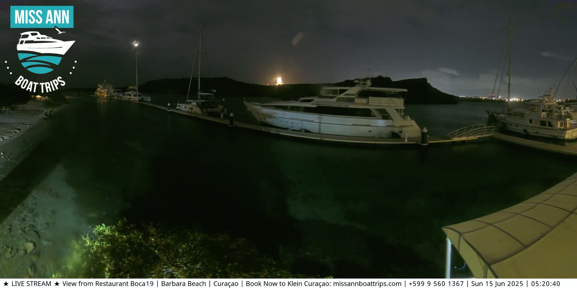 Several yachts are docked at a marina at night under a dark sky.