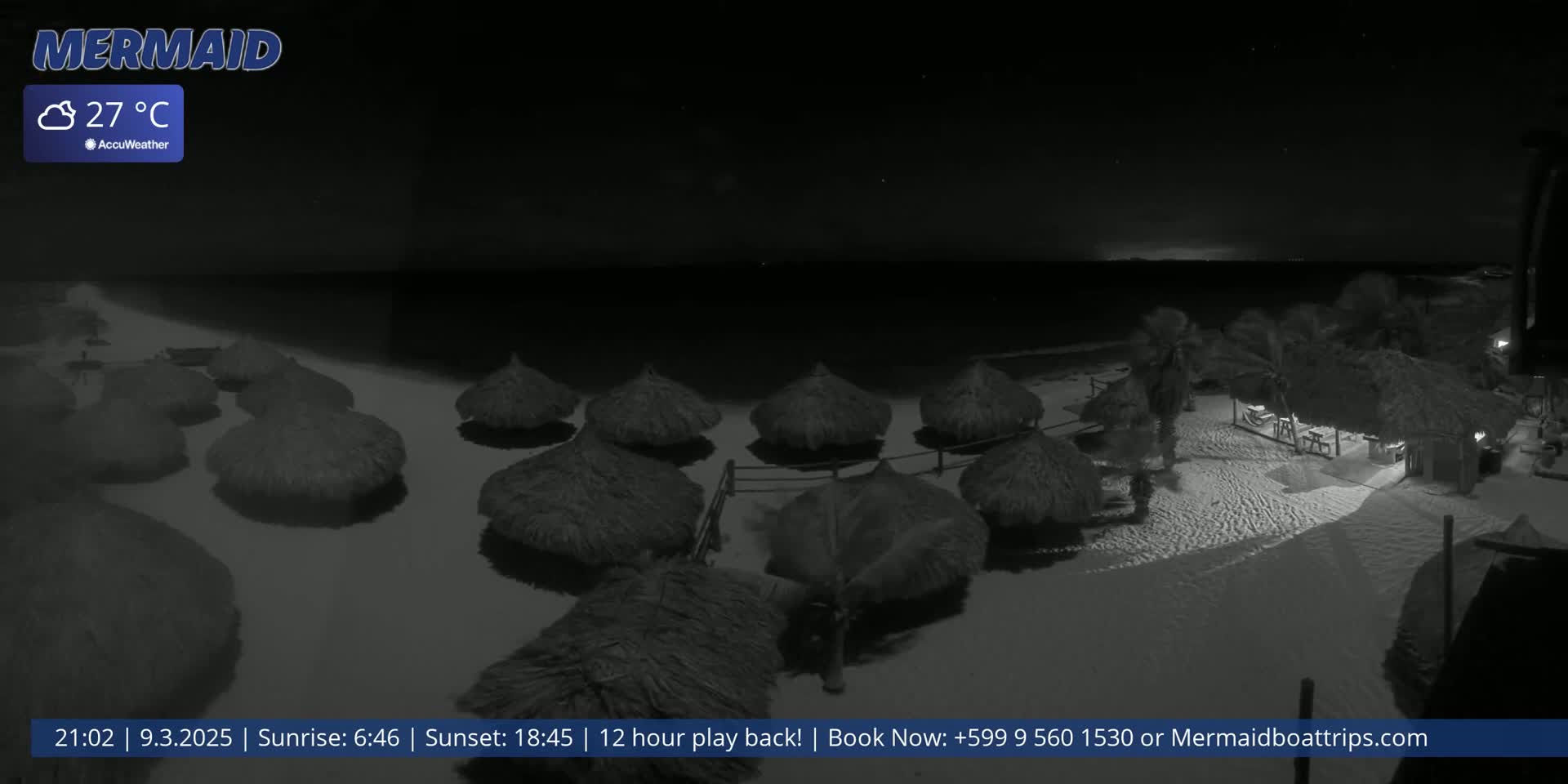 A nighttime beach scene shows numerous thatched-roof beach umbrellas on a sandy shore under a clear, dark sky, with a temperature of 27°C.