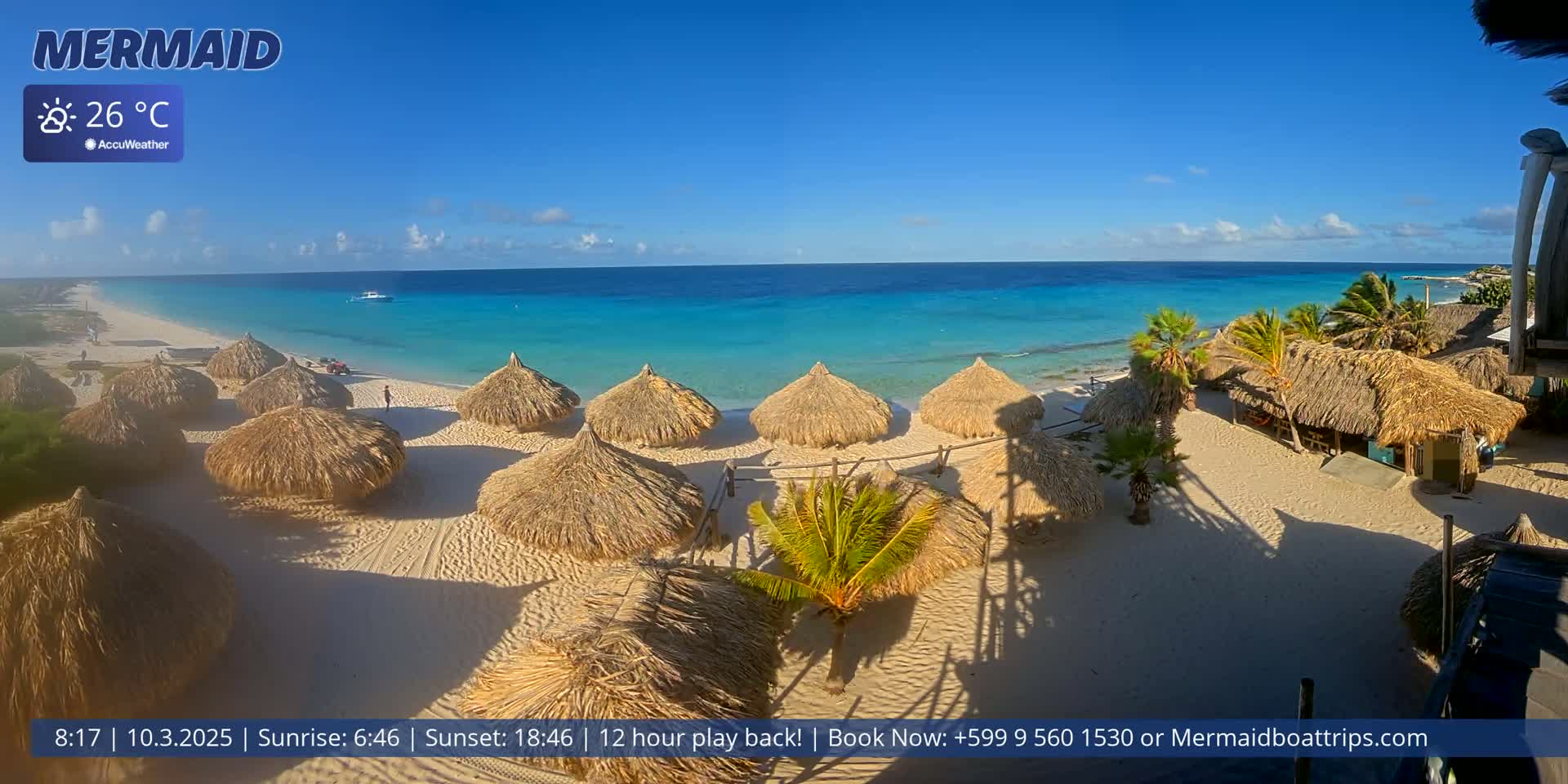 A beach with numerous thatched-roof structures and turquoise water under a sunny sky.