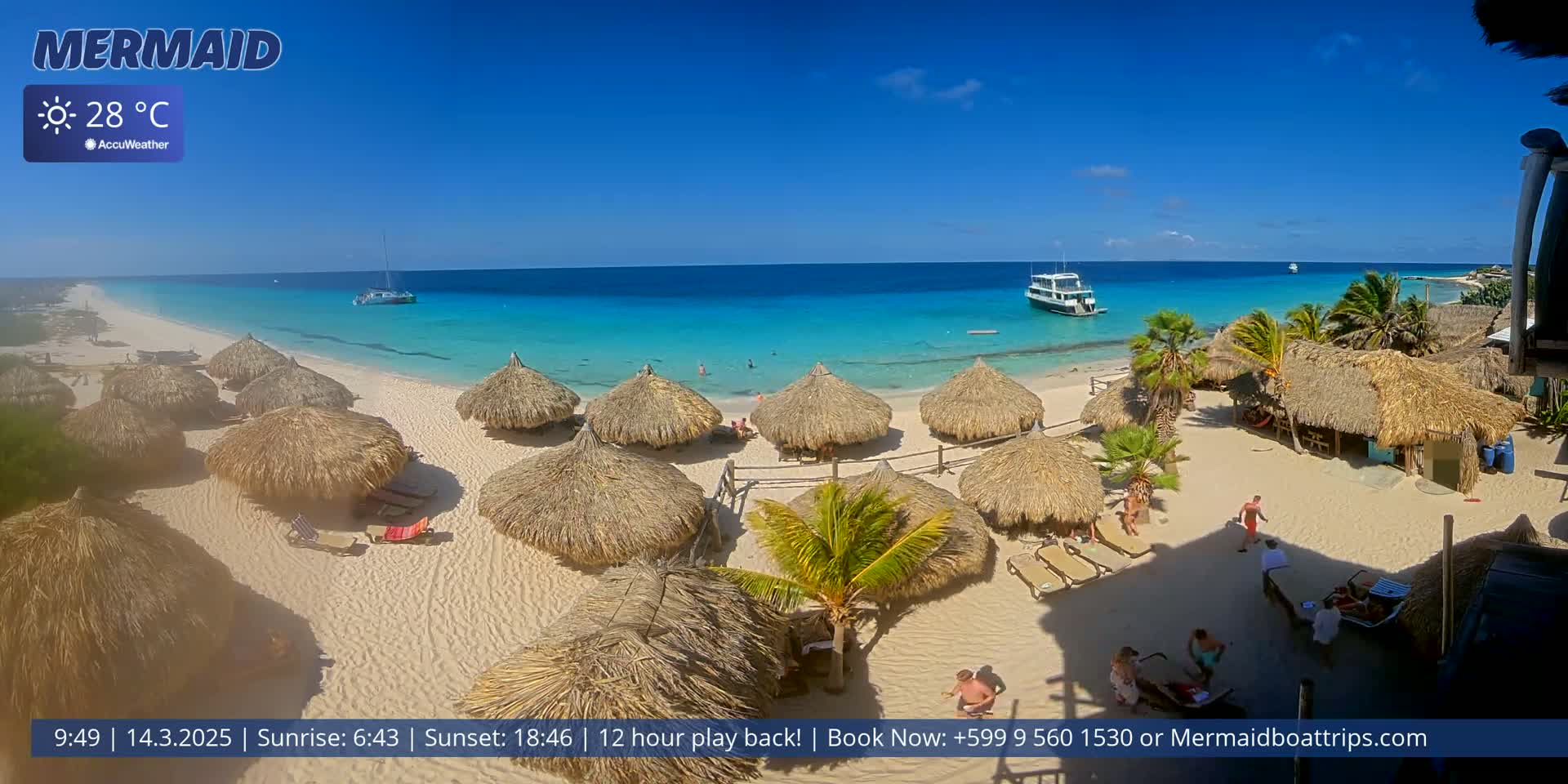 A sunny beach with turquoise water, numerous thatched-roof huts, and a boat offshore.