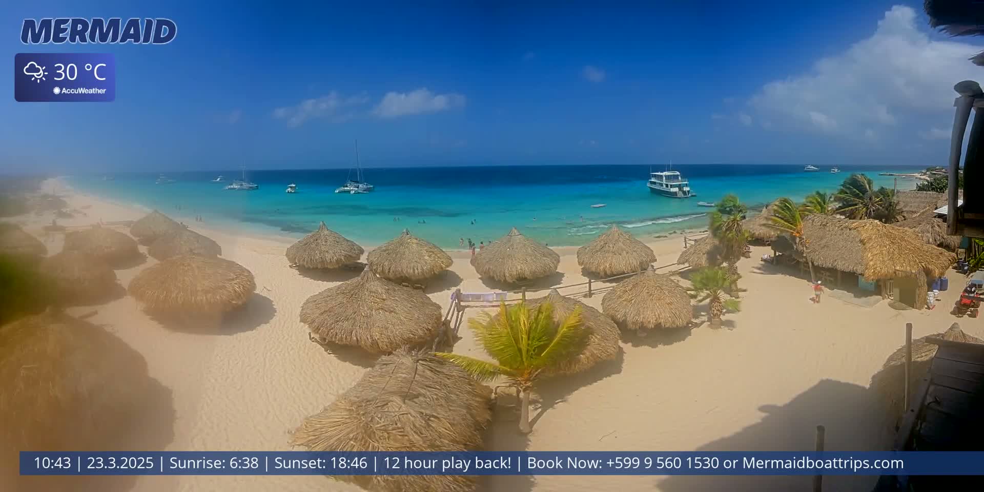 A sandy beach with turquoise water, thatched-roof huts, and several boats offshore under partly cloudy, sunny skies, with the temperature at 30°C.