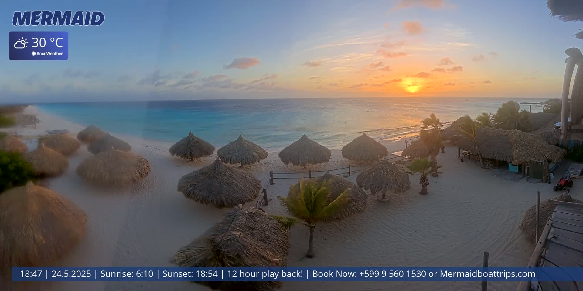 A beach at sunset with numerous thatched-roof umbrellas on a sandy shore, clear turquoise water, and a 30°C temperature.