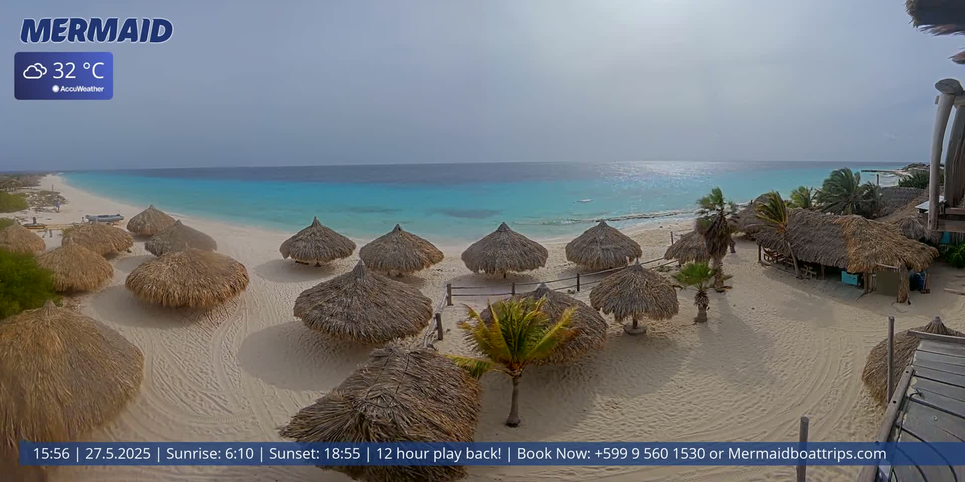 A beach with numerous thatched-roof umbrellas and turquoise water under partly cloudy skies.