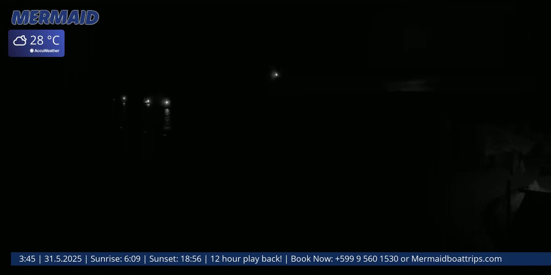 A dark, nighttime scene shows several faint lights on the water under a clear, 28°C sky.