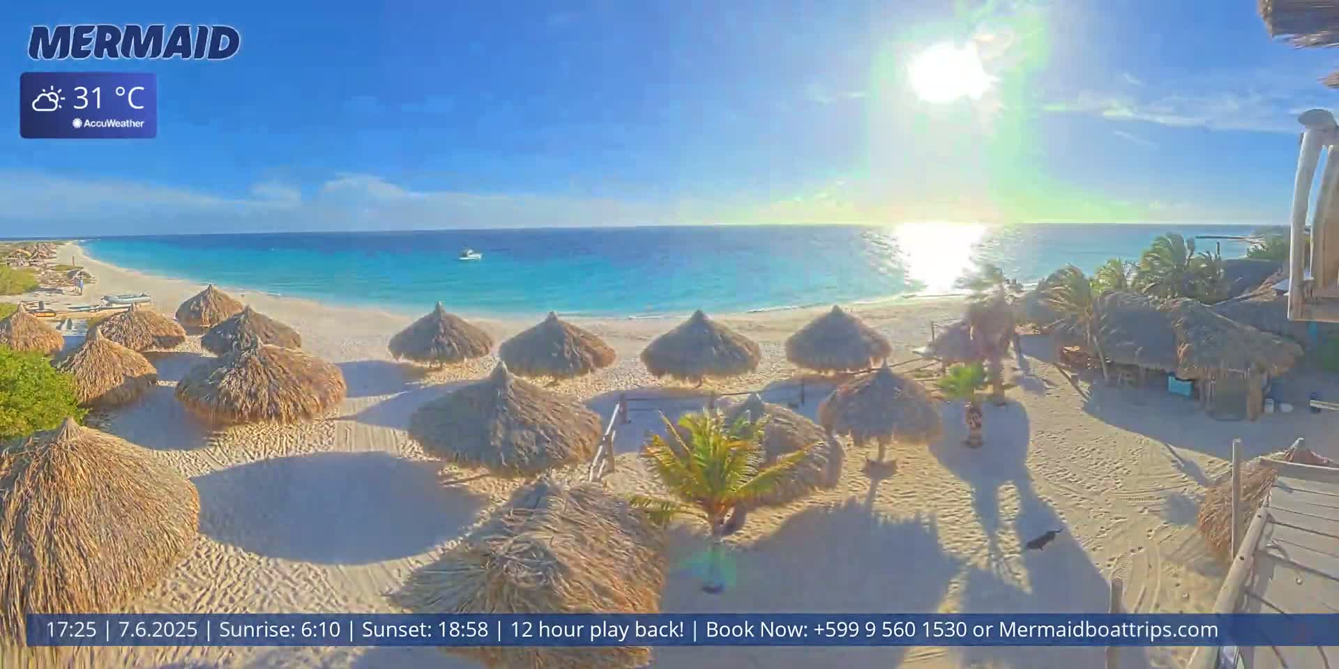 A sunny beach scene with numerous thatched-roof beach umbrellas on a white sand beach, clear turquoise water, and a bright sun in the sky.