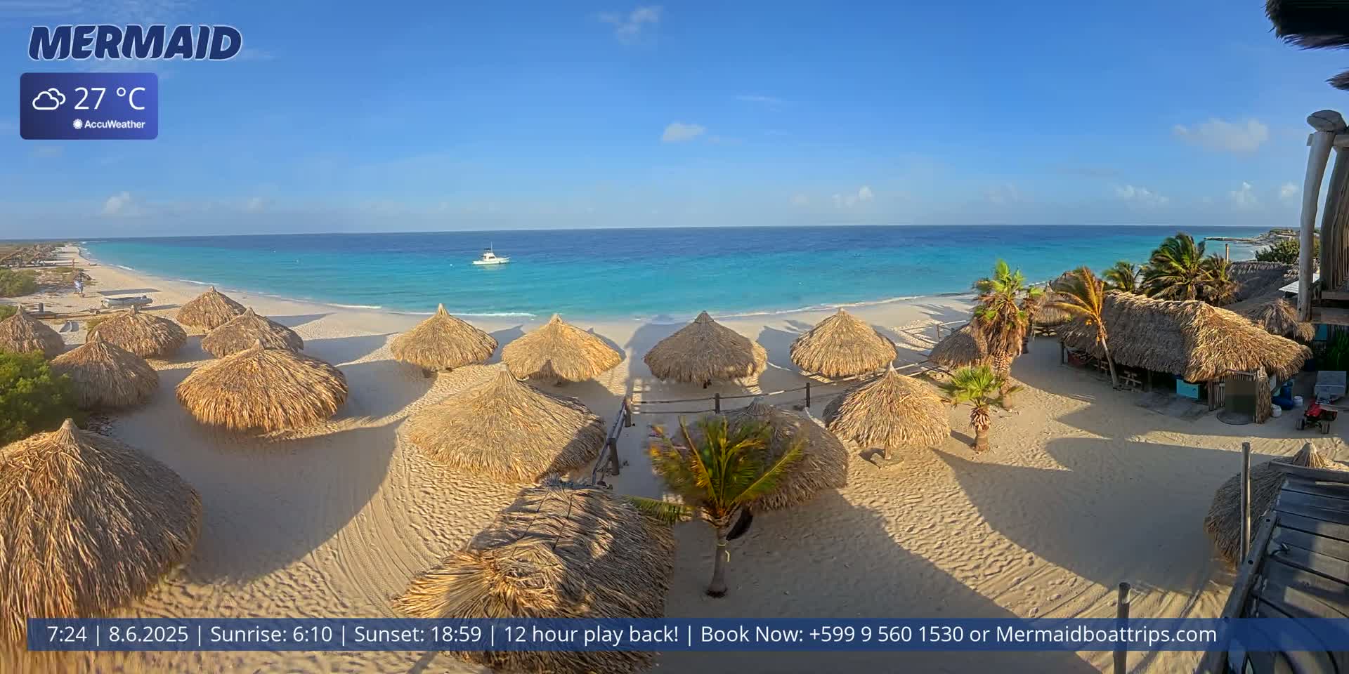 A beach with numerous thatched umbrellas, a boat on the turquoise water, and palm trees under a mostly clear sky.