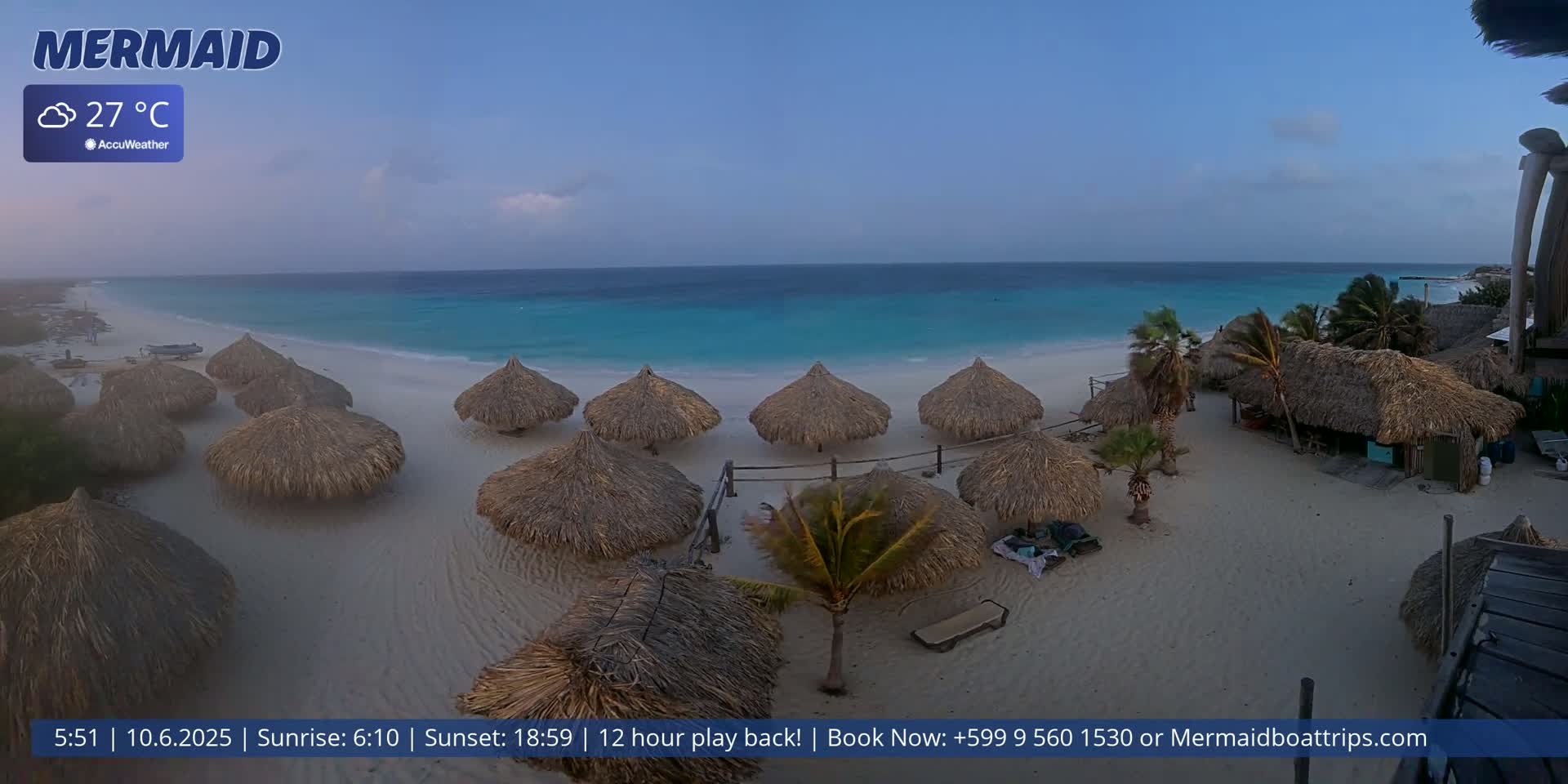 A beach with numerous thatched-roof umbrellas, palm trees, and turquoise water under a partly cloudy sky.