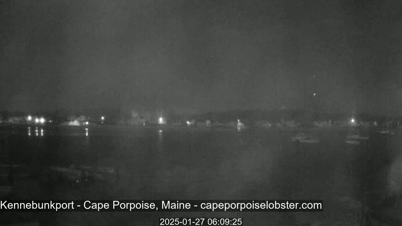 A nighttime, low-light view shows a dark body of water with faintly visible lights across the far shore.