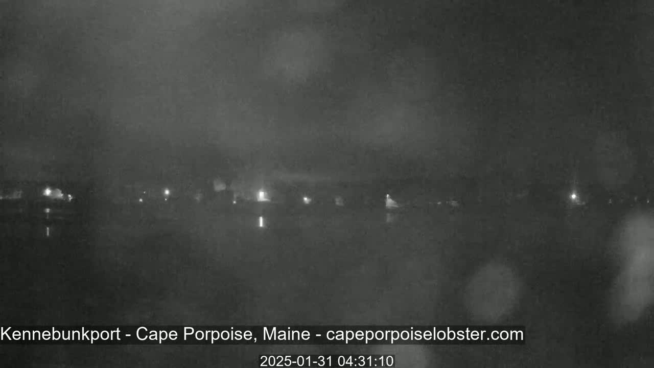 A nighttime, hazy view of a calm body of water with dimly lit buildings visible across the water.