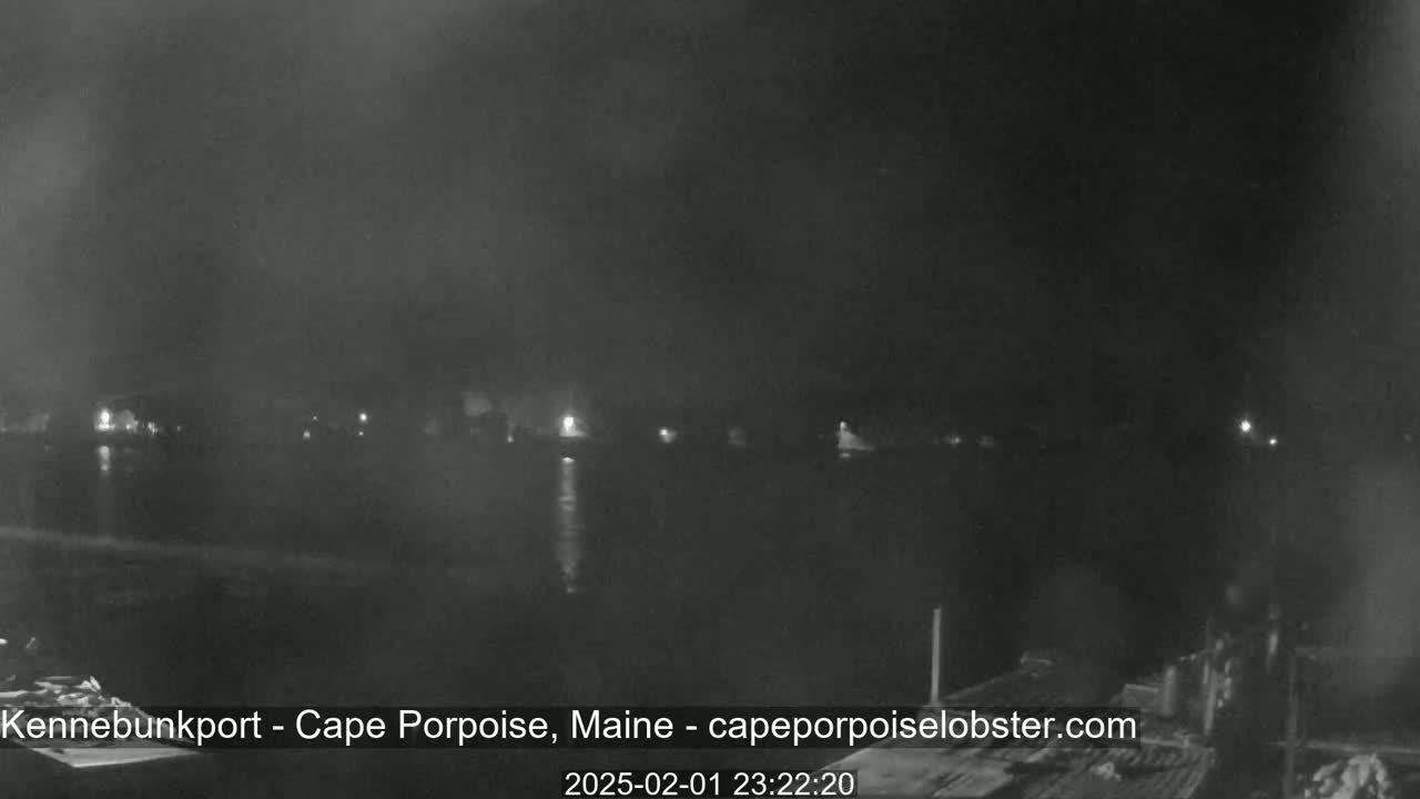 A nighttime, hazy view of a calm body of water with faint lights on the opposite shore.