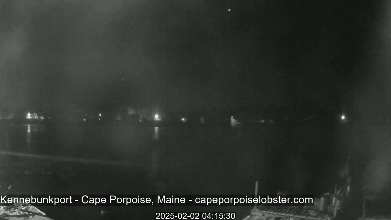 A nighttime, low-light view of a calm body of water with dimly lit buildings on the far shore.