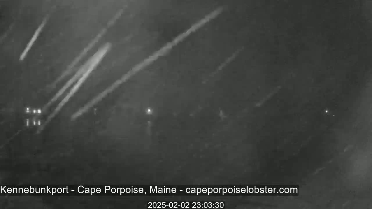A nighttime, low-light outdoor scene shows streaks of light across a dark sky, possibly indicating heavy snow or rain.