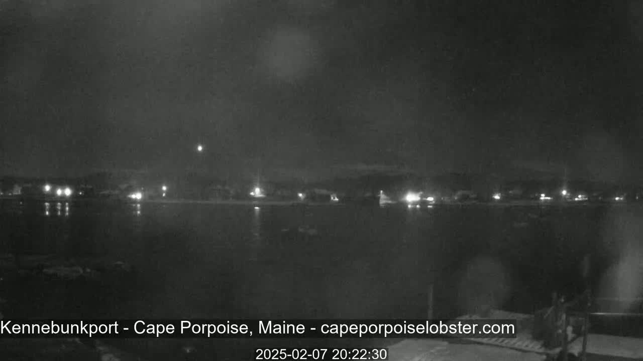 A nighttime, low-light view shows a dark body of water reflecting a dimly lit shoreline.