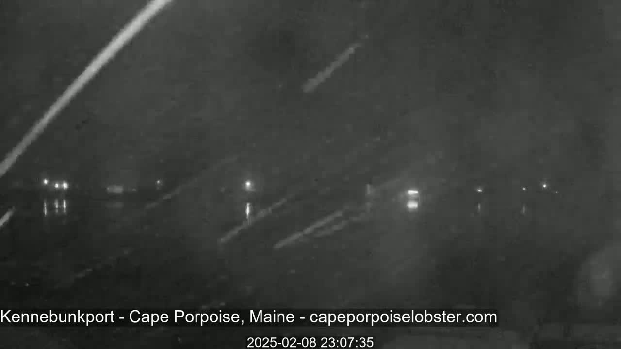 A nighttime, blurry, low-light view of a road with faint lights and streaks of possible rain or snow.