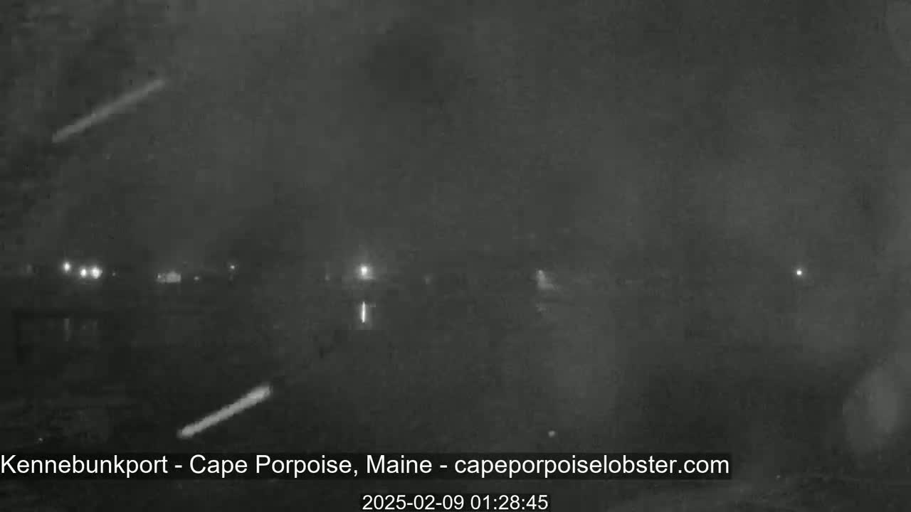 A nighttime, foggy view shows faint lights in the distance.