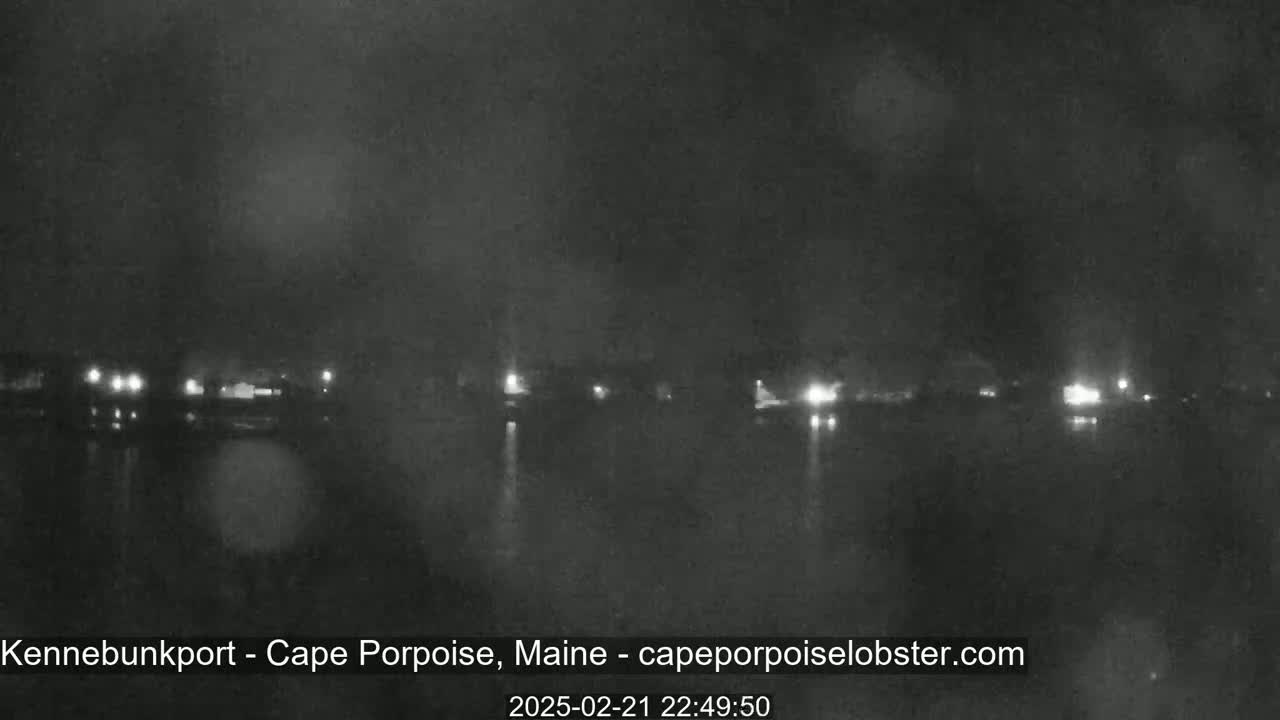 A nighttime, hazy view of a calm body of water with faintly visible lights on the opposite shore.