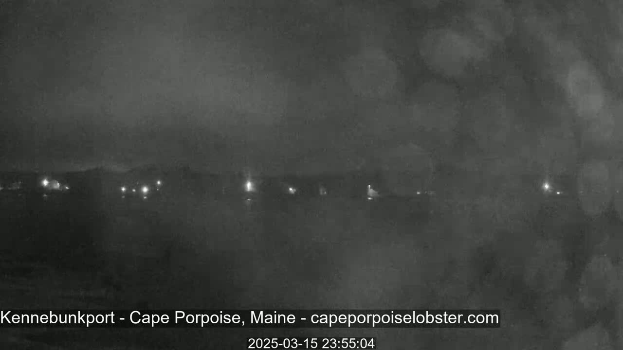 A nighttime, hazy view shows a dark shoreline with a few distant lights.