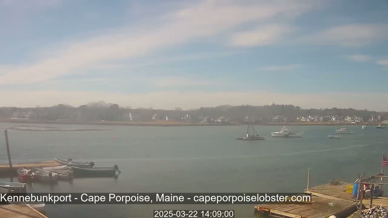 A calm body of water with several boats and a distant shoreline under a partly cloudy sky.