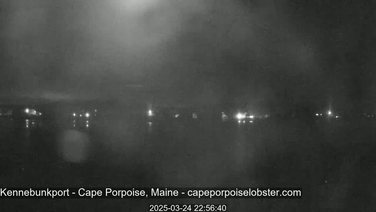 A nighttime, hazy view of a body of water with faintly visible lights on the opposite shore.