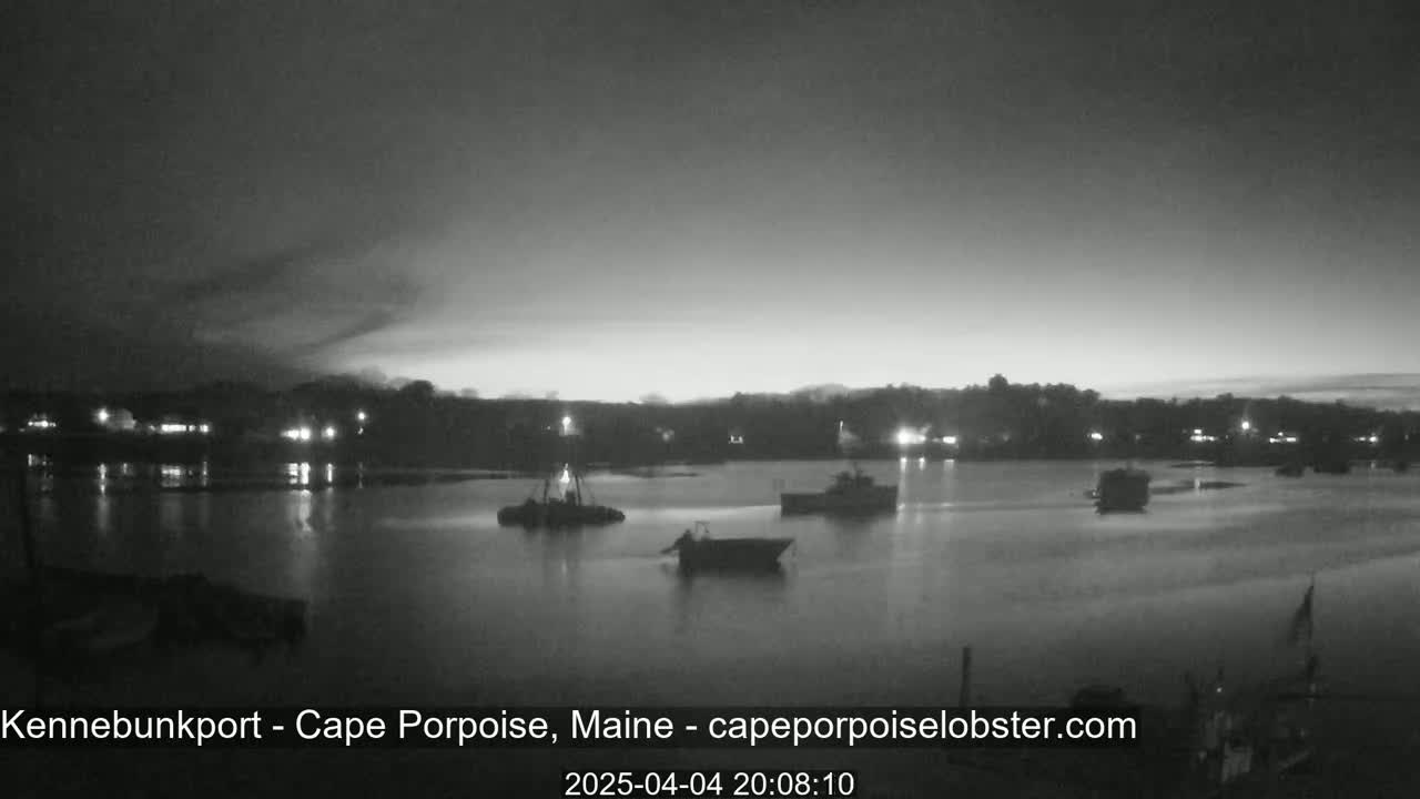 Several boats are moored in a calm body of water at twilight under a mostly clear sky.