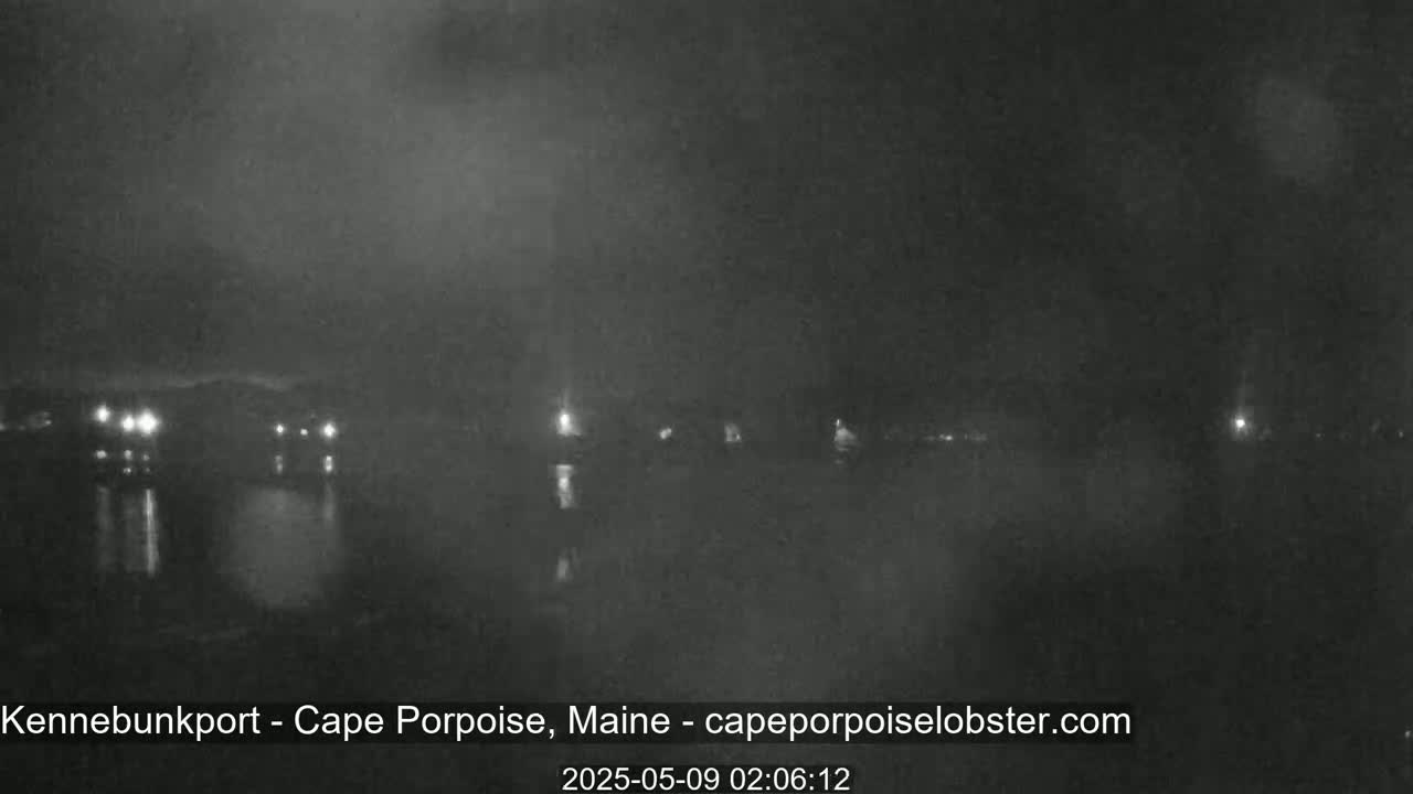 A nighttime, hazy view of a dark body of water with a few faint lights visible on the far shore.