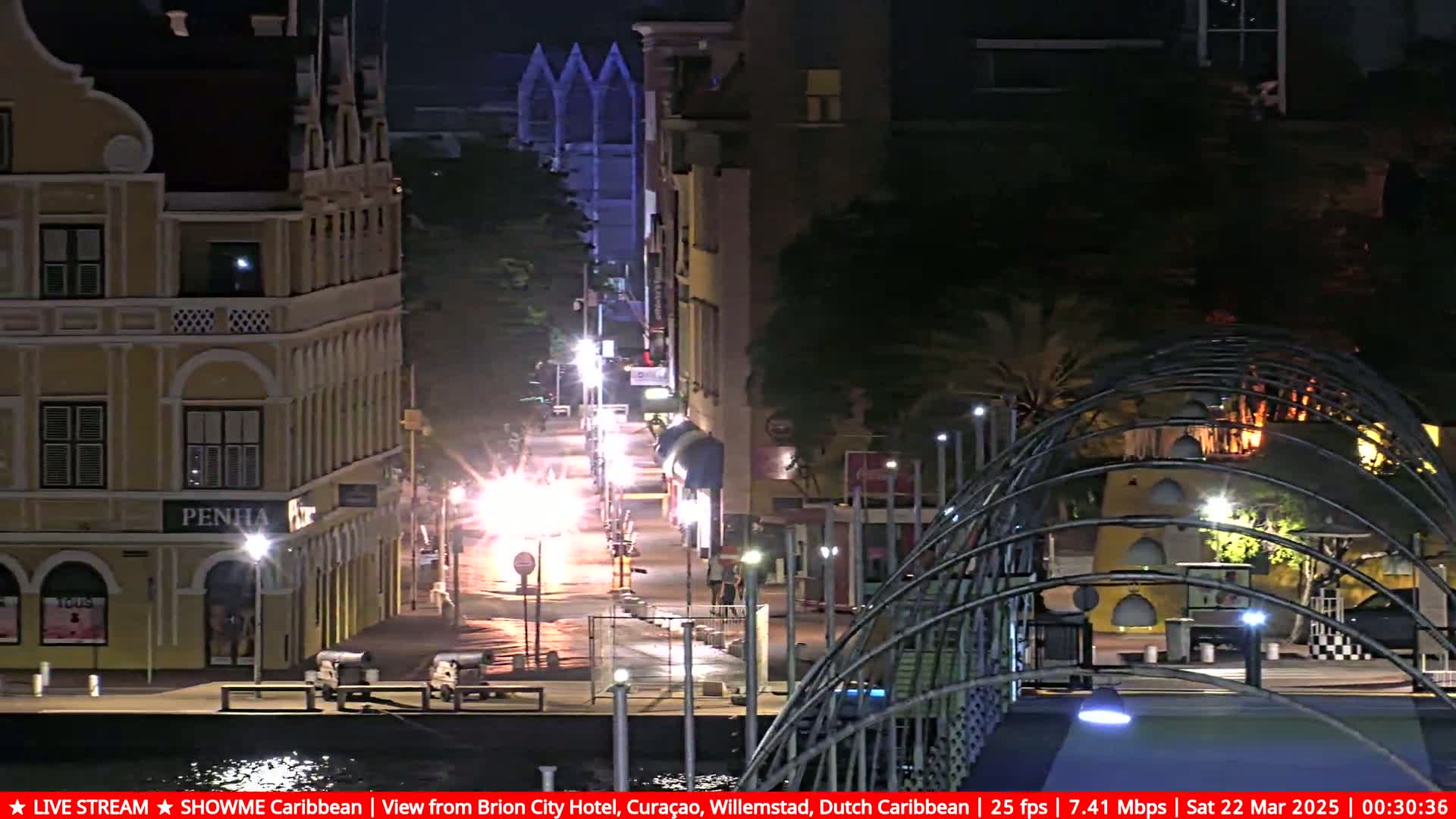 A nighttime street scene shows illuminated buildings and a bridge, with cars visible on a roadway.