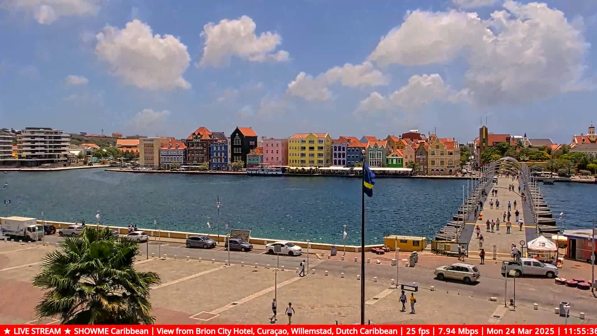 A colorful waterfront town with a pontoon bridge and clear skies is visible on a sunny day.