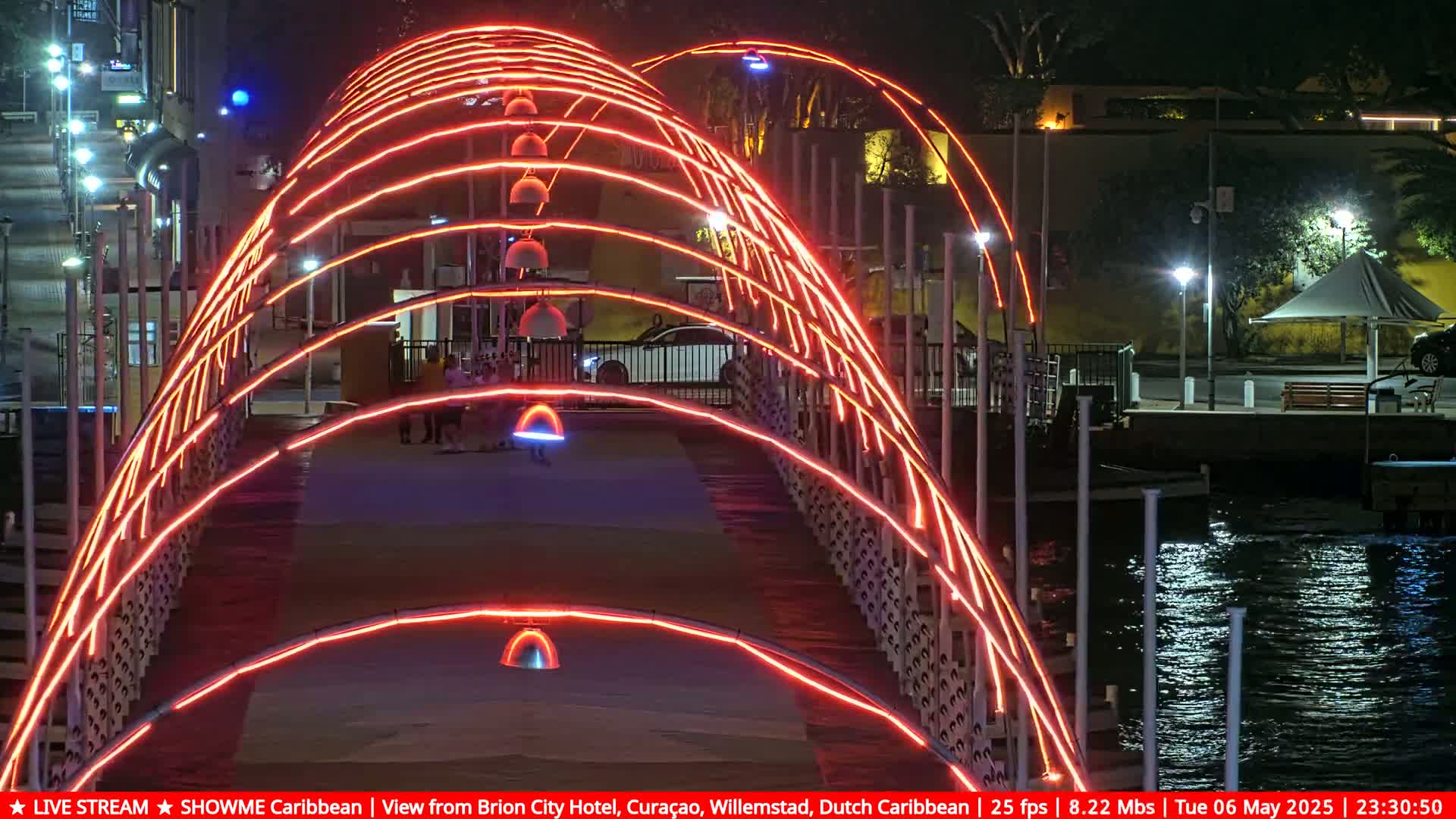 A bridge at night, illuminated with bright orange lights, overlooks dark water.
