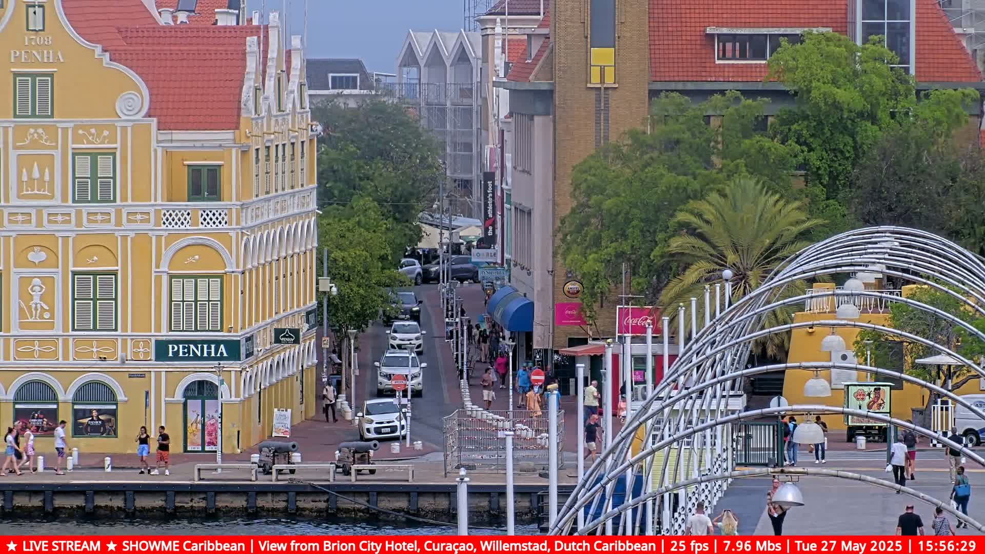 A waterfront street scene with pedestrians, cars, and colorful colonial-style buildings under an overcast sky.