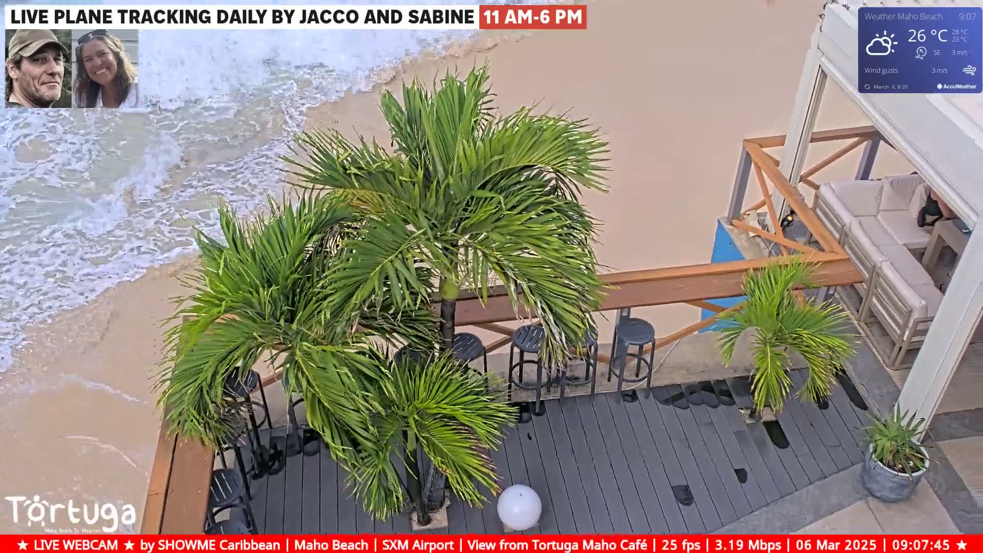 An outdoor scene shows a beach with gentle waves, palm trees on a gray deck with bar stools and a white couch, under sunny skies.