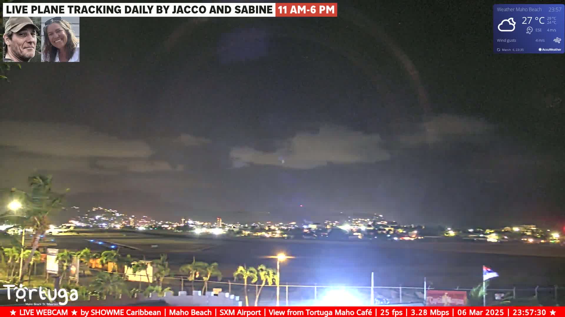 A nighttime view of an airport runway and surrounding city lights under a partly cloudy sky with a 27°C temperature and light wind.