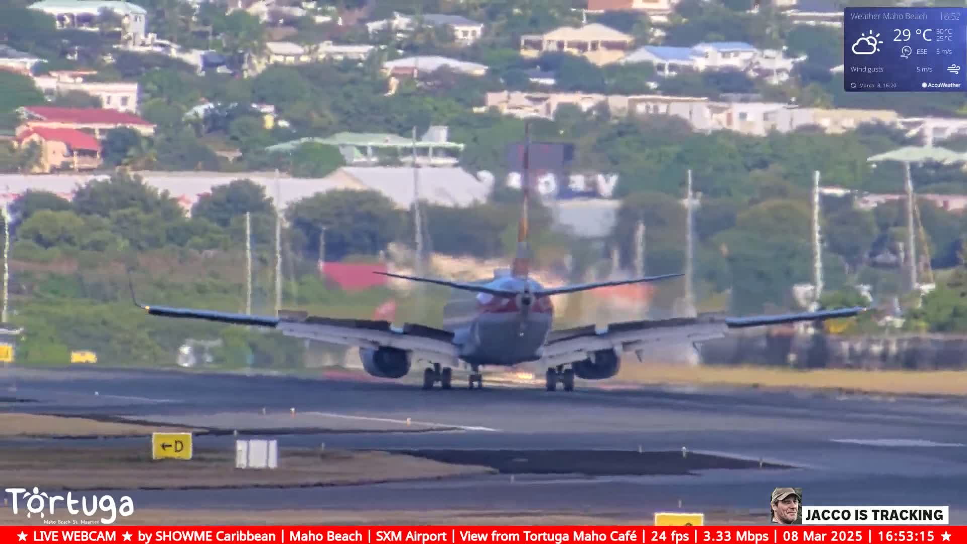 A commercial airplane is landing on a runway, with partly cloudy skies and wind gusts.