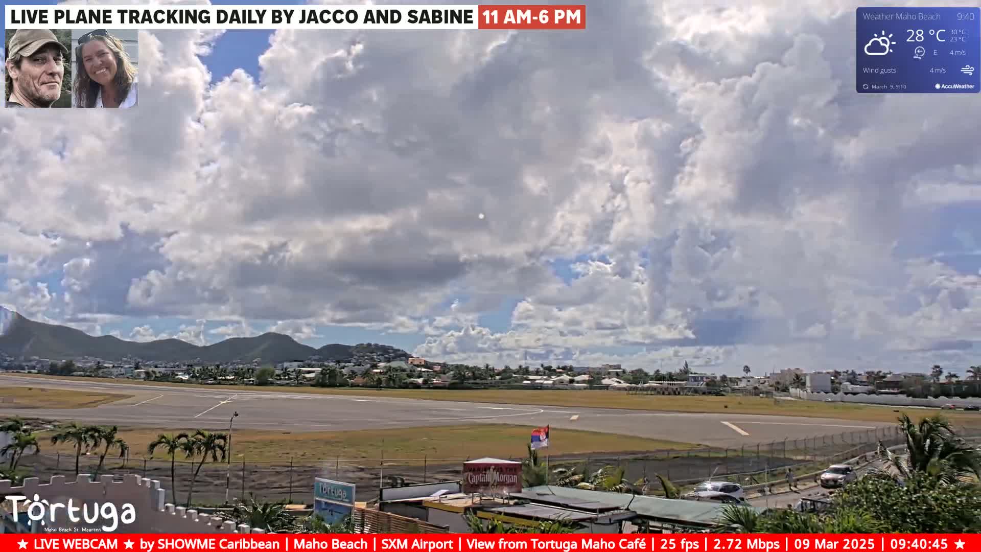 A partly cloudy sky over an airport runway and surrounding buildings.