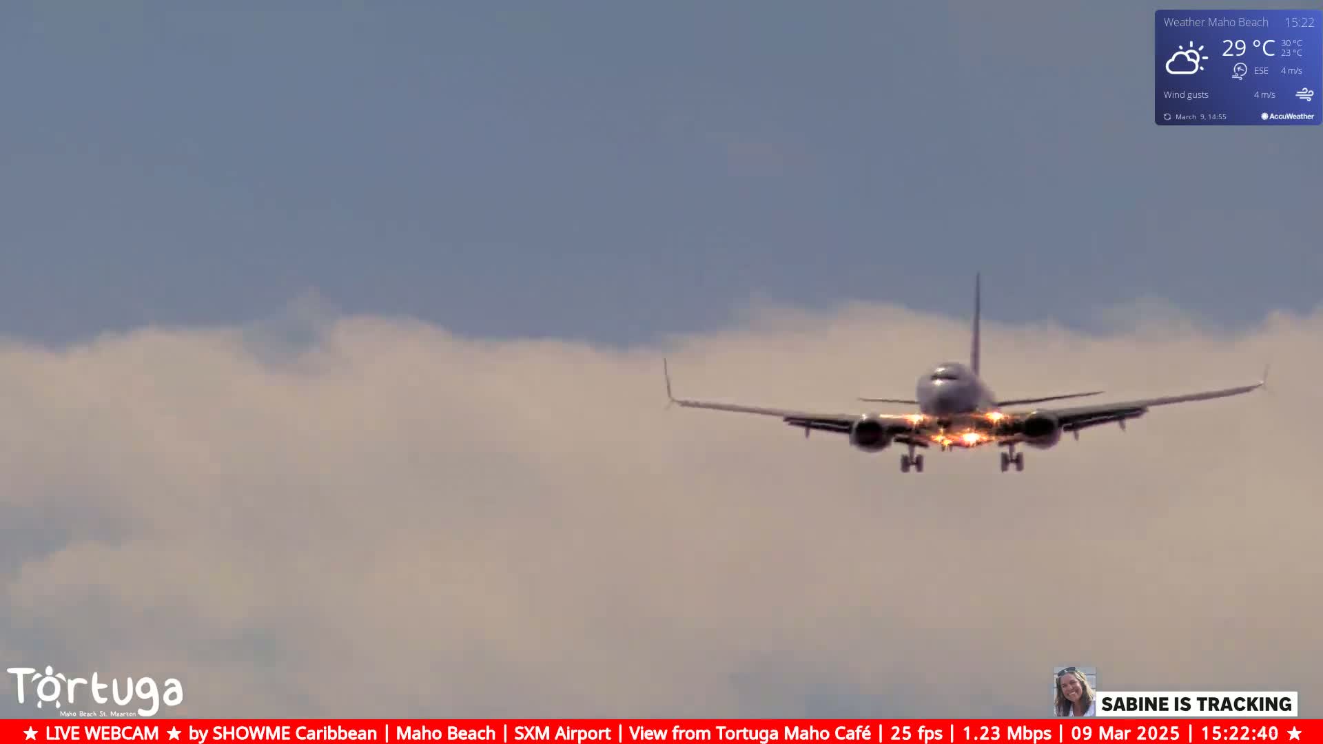 A passenger plane is approaching for landing under a partly cloudy sky.