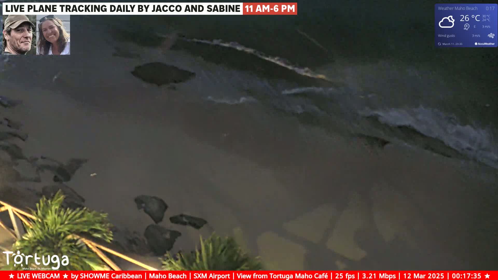 A dark beach at night with gently lapping waves under a partly cloudy sky, the temperature being 26°C.