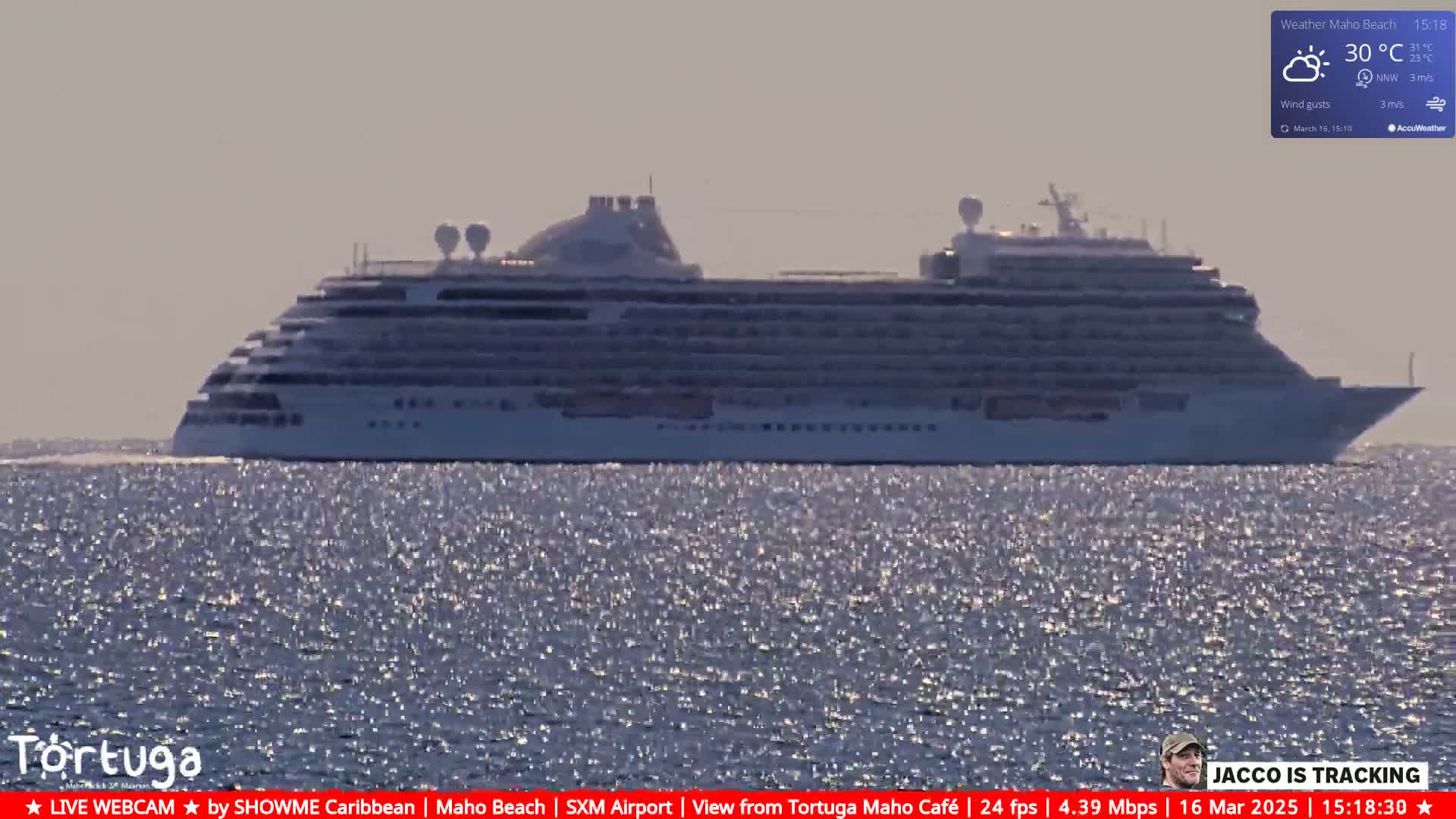 A large cruise ship sails on a calm, sunny ocean.