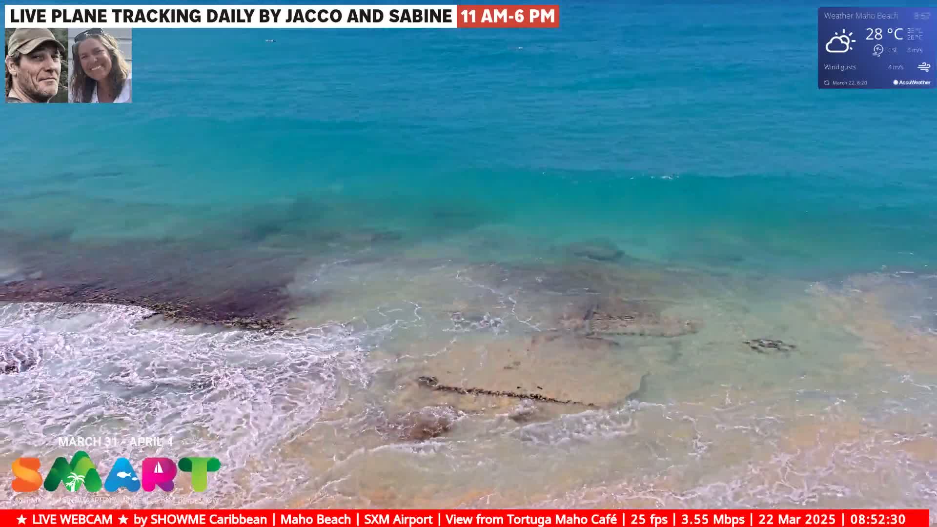 A high-angle view shows a beach with clear, turquoise water lapping gently on the shore under sunny skies, with a temperature of 28°C and a light wind.